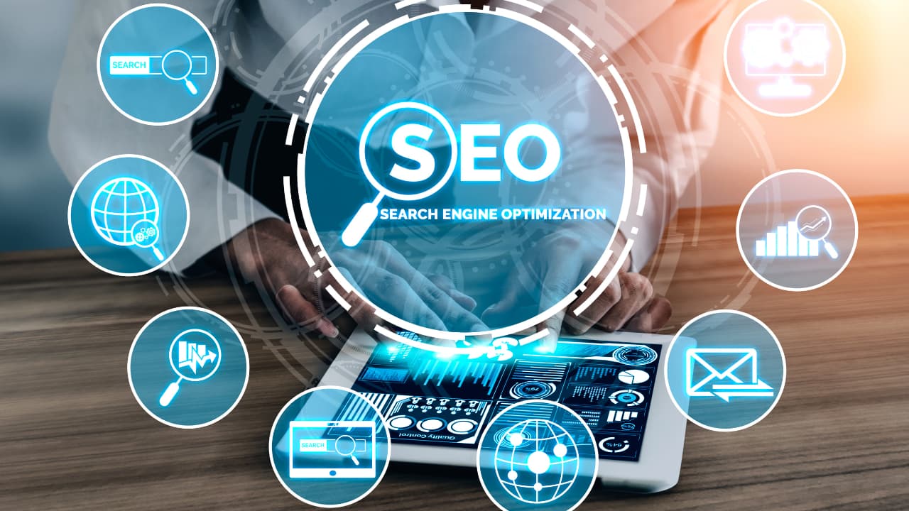 A person uses a tablet displaying analytics graphs, surrounded by floating SEO-related icons like a magnifying glass and email, symbolizing digital marketing strategies.