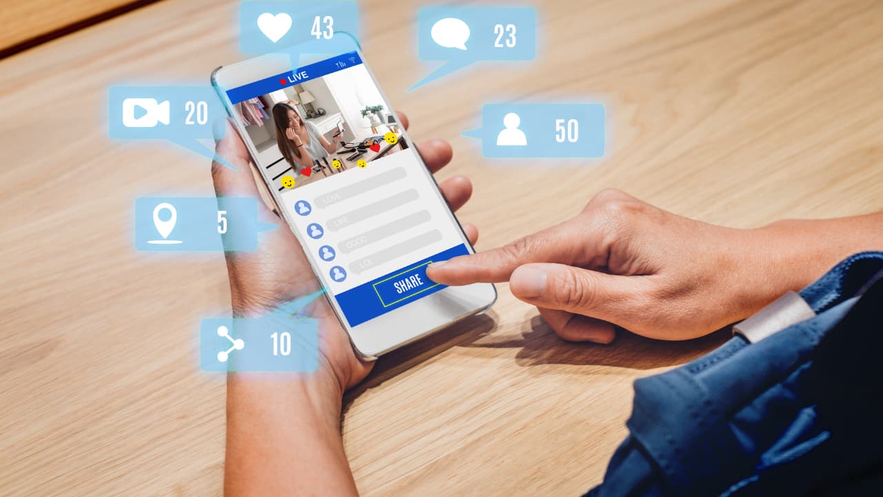 A person holding a smartphone showing a live stream with interactive icons, like hearts and comments, hovering above. The tone is modern and connected.