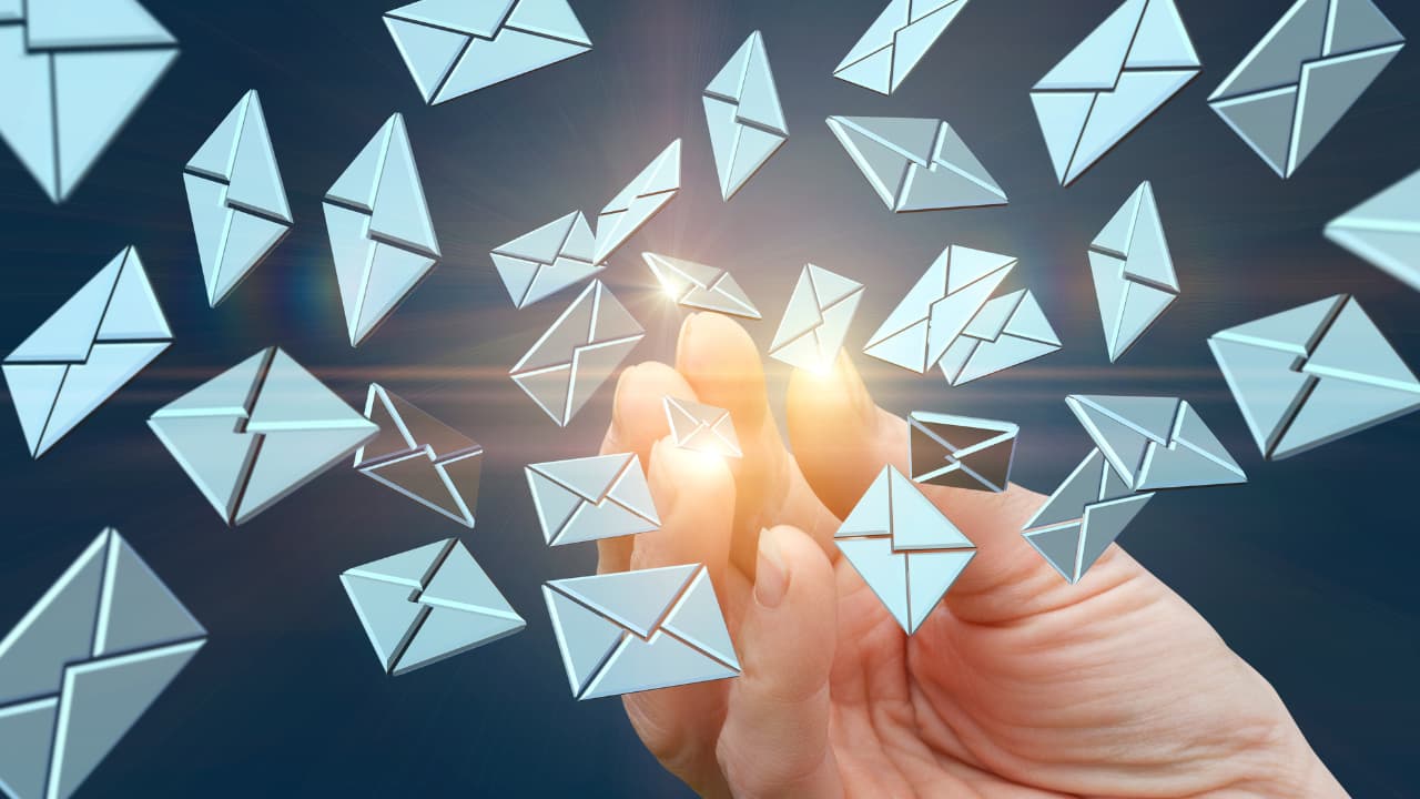 A hand reaches towards floating email icons, symbolizing digital communication. The image conveys a futuristic and dynamic atmosphere.