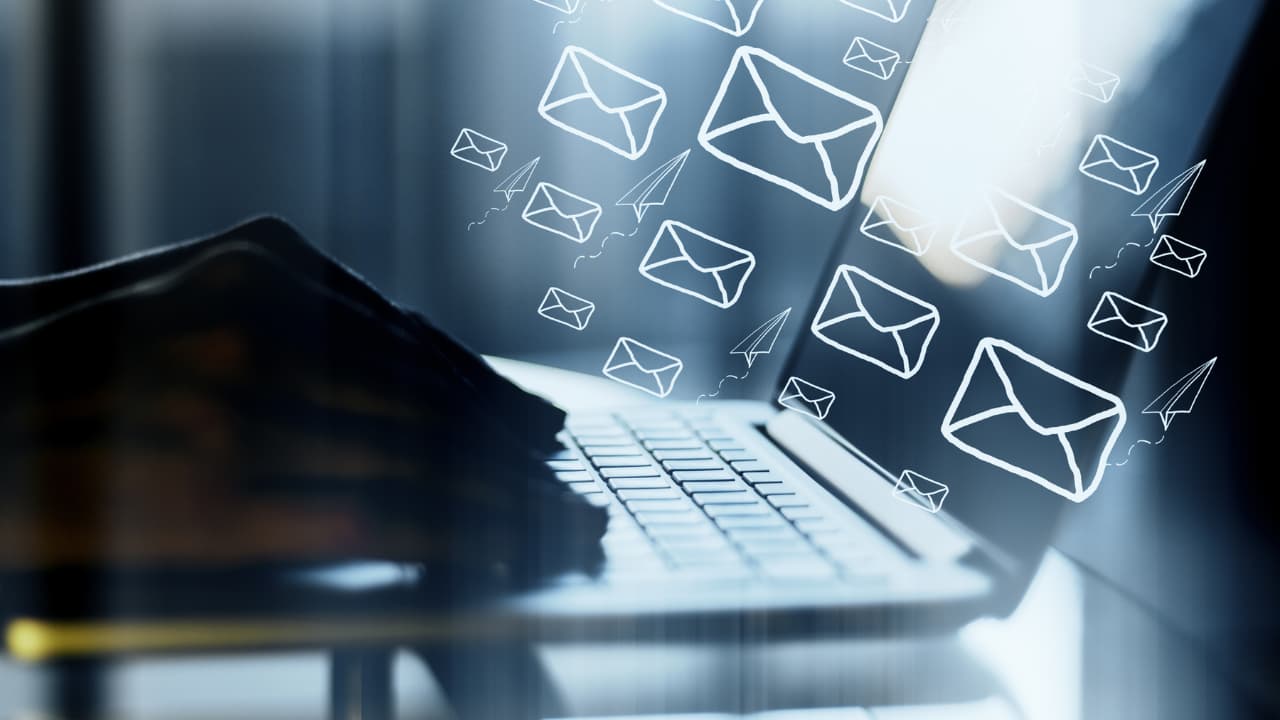 Hands typing on a laptop keyboard, with digital envelopes and paper planes illustrating email sending. The scene is dynamic and futuristic.