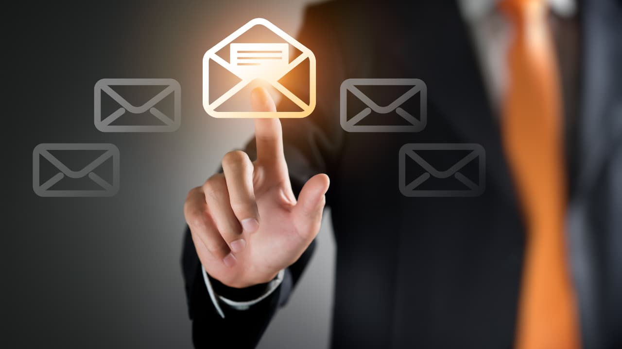 A person in a suit and orange tie touches a glowing email icon amidst floating envelope symbols, conveying concepts of communication and technology.